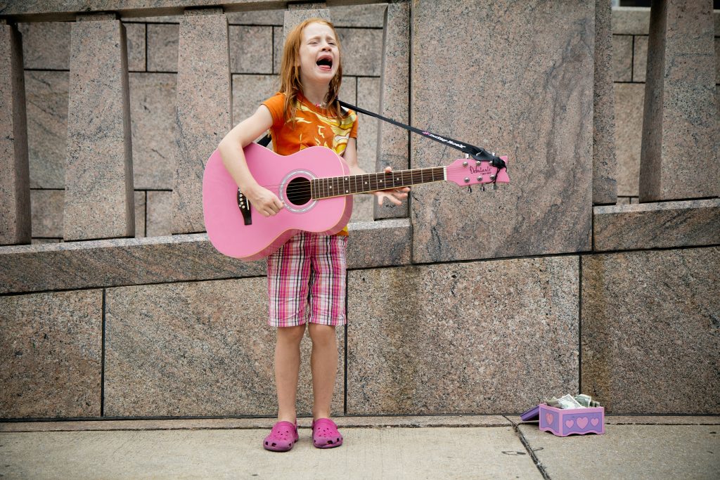 girl singing and playing guitar near wall