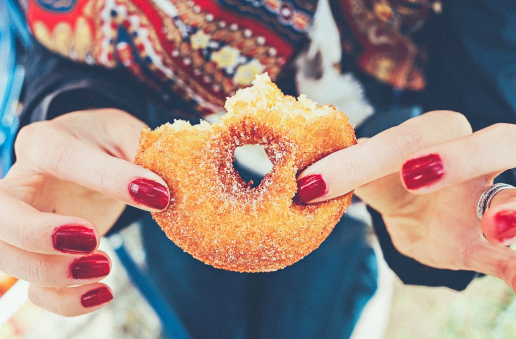 Woman holding donut - the kind of food that worsens qi stagnation!