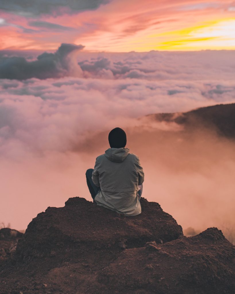 Man sitting on cliff - try Meditation to Manage Qi Stagnation!