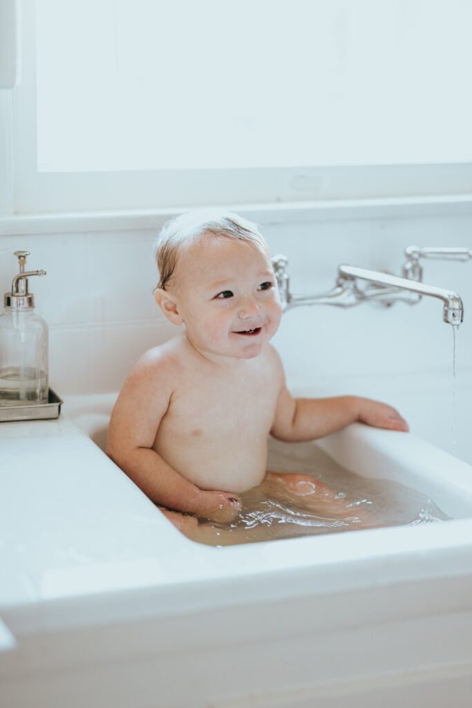 topless baby on white bathtub