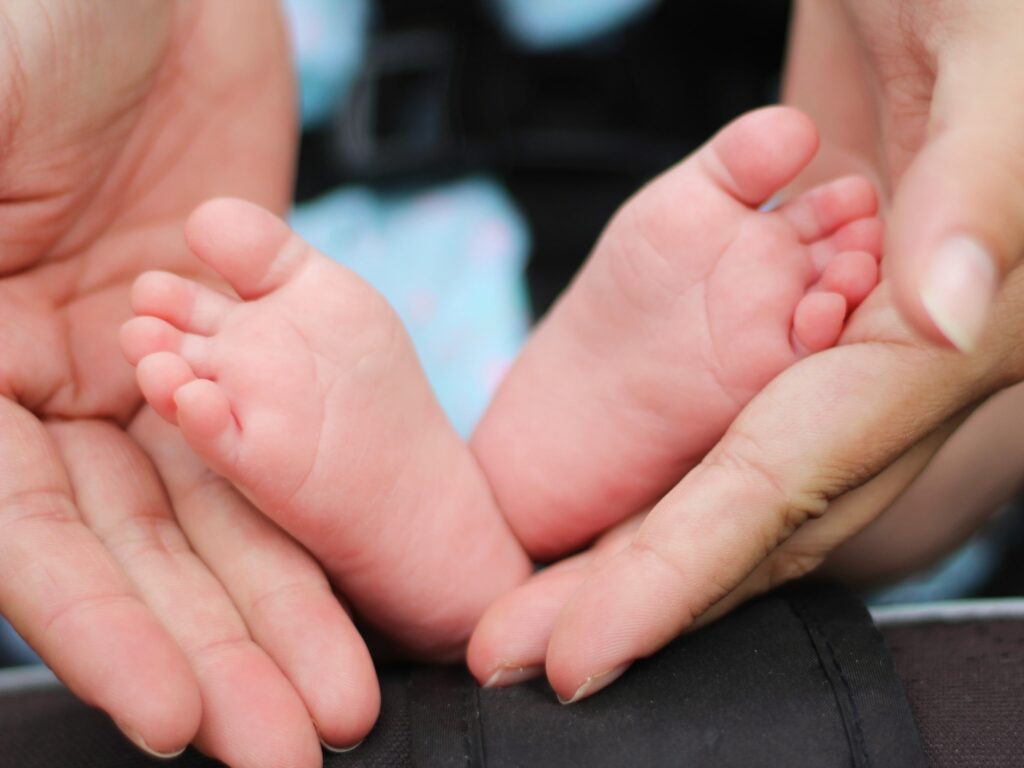 person holding baby feet - massage on children