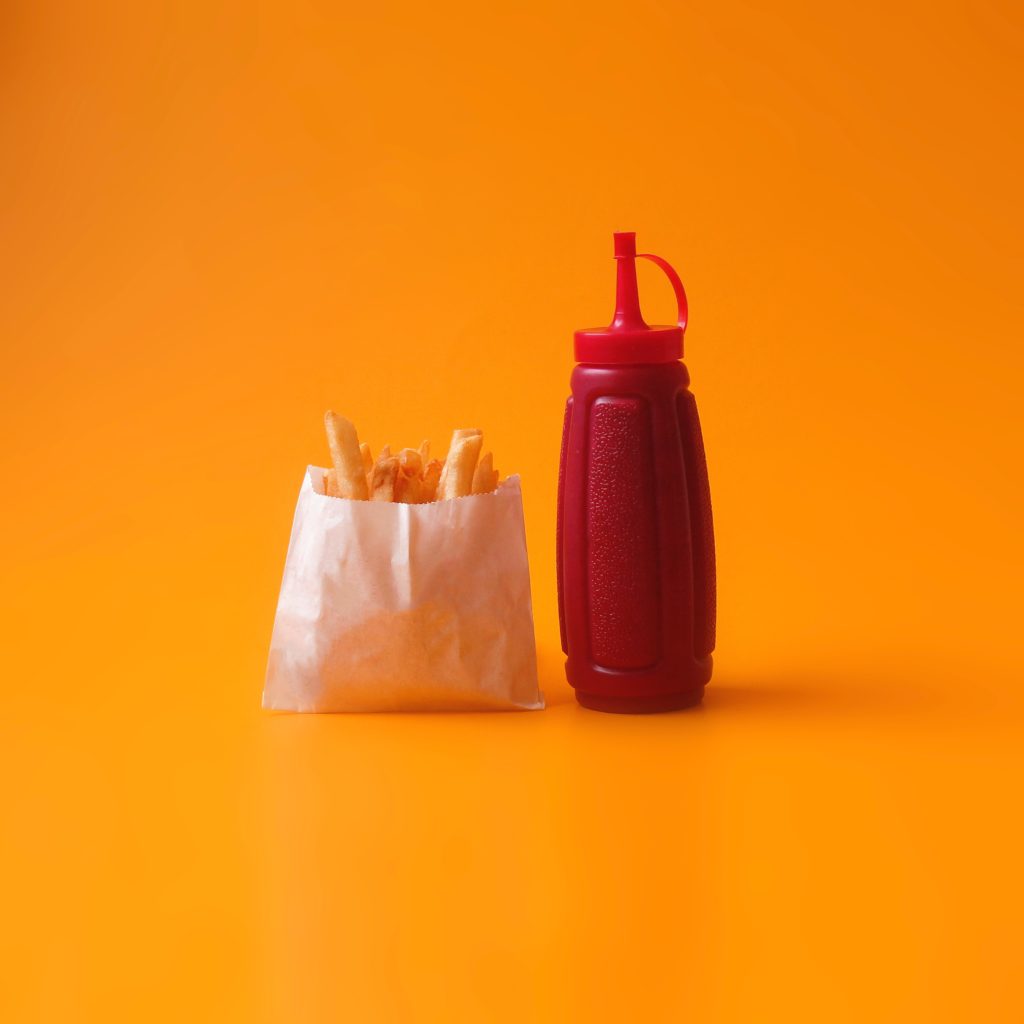 fried fries in white pack beside red squeeze bottle
