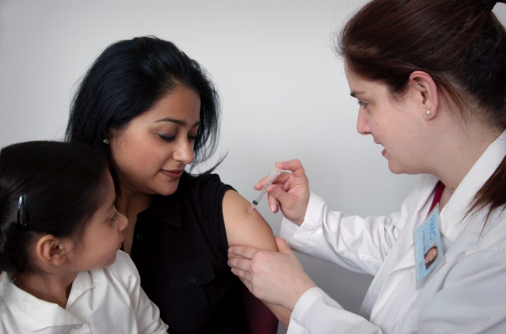 woman injecting woman's arm carrying child: vaccination is metabolised by your liver, which can disrupt Liver Function.
