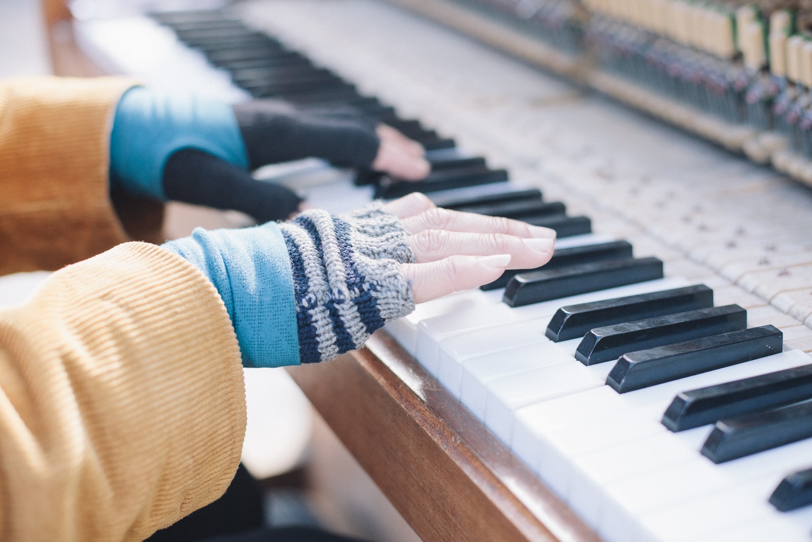 person playing piano wearing mittens for cold hands