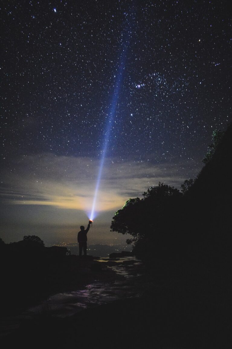 man holding flashlight pointing towards sky