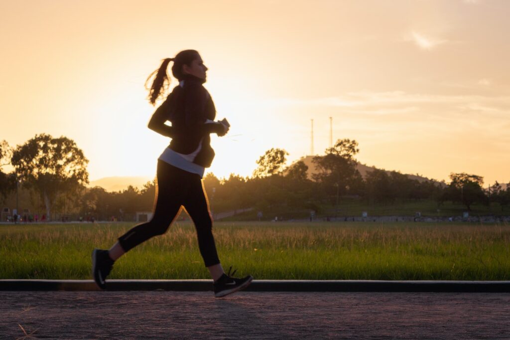 jogging often causes knee pain from qi stagnation and blood stasis: woman in black sports bra and black pants running on water during sunset