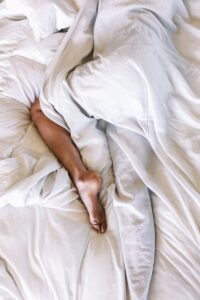 woman covered with white blanket, in position to ease sciatica